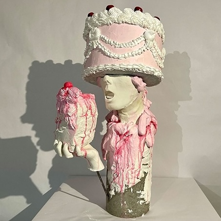 Ceramic sculpture of a figure wearing a pink cake-like hat